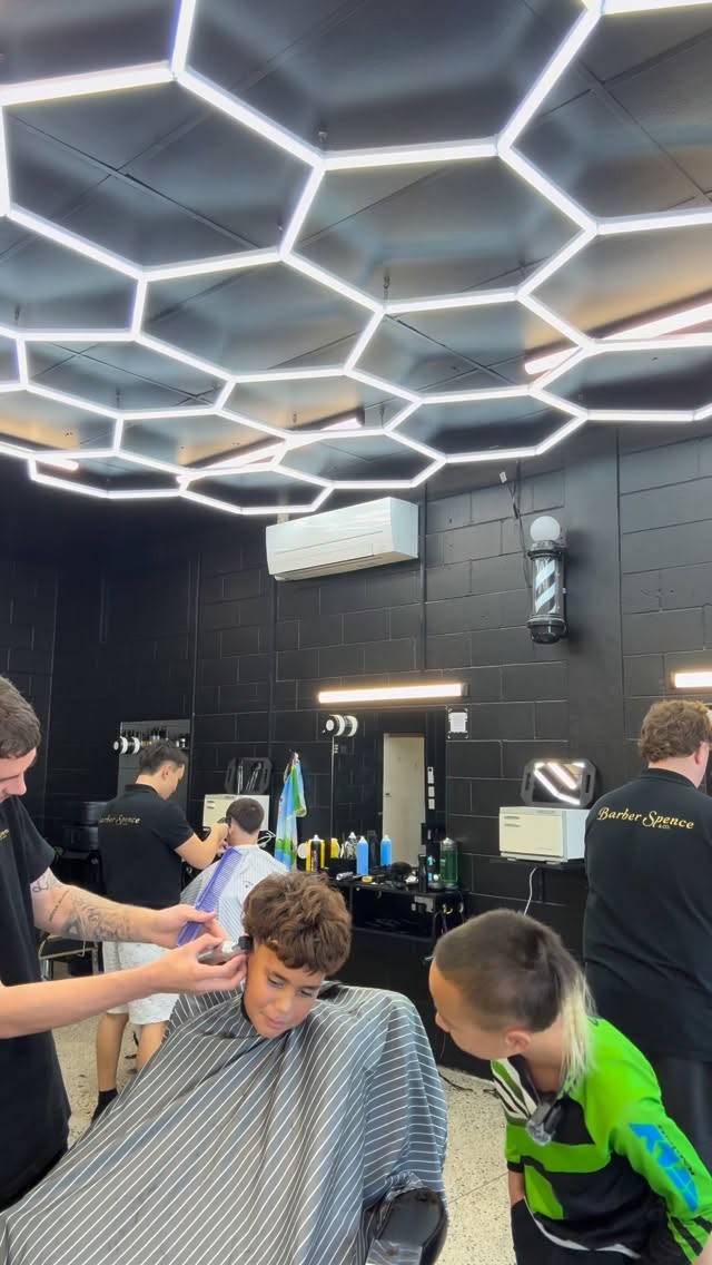 A kids cut in progress beneath the hexagonal shop lights